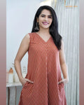 Sleeveless rust-orange dress with white diagonal stripes and V-neckline, worn with earrings.