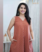 Sleeveless rust-orange dress with white diagonal stripes and V-neckline, worn with earrings.