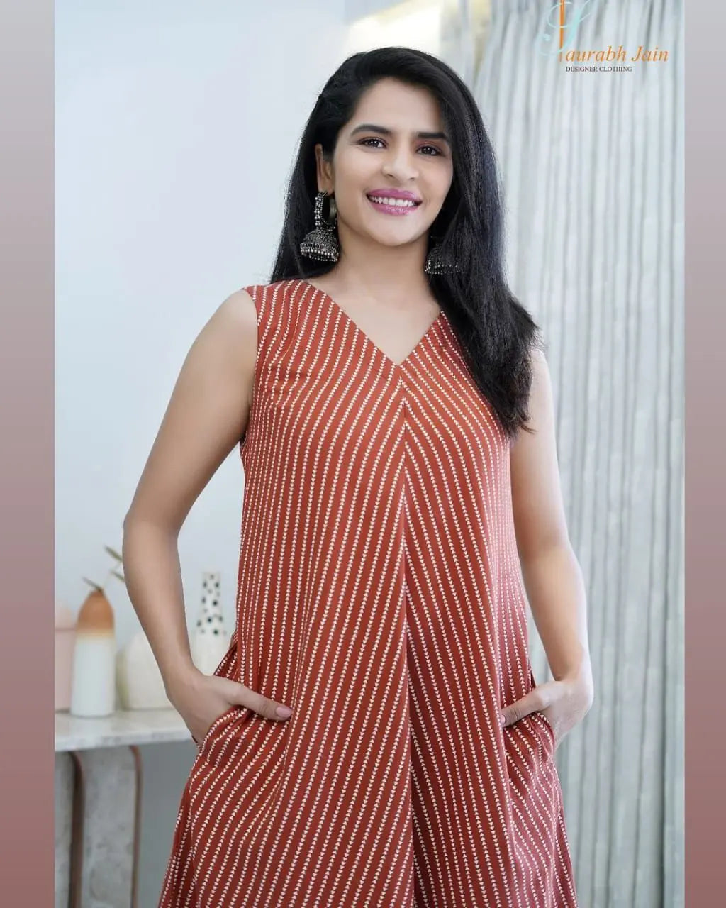 Sleeveless rust-orange dress with white diagonal stripes and V-neckline, worn with earrings.