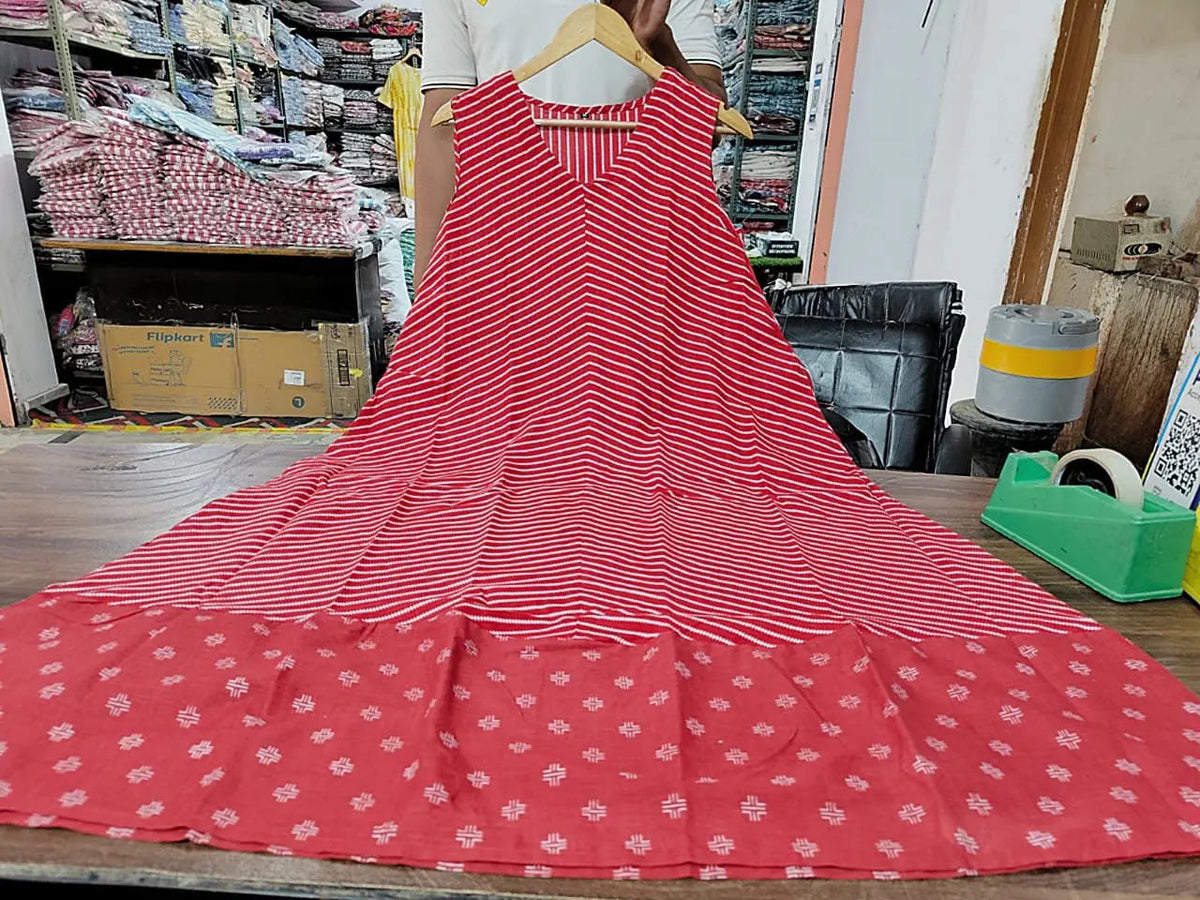 Sleeveless red dress with white stripes and floral border, hanging on wooden hanger.