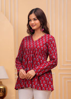 Red printed long kurti top with flared hem and V-neck, worn with long sleeves.