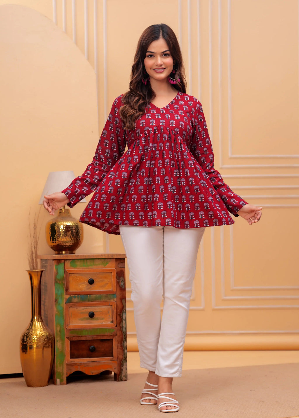 Red printed long flared kurti with full sleeves paired with white slim pants.