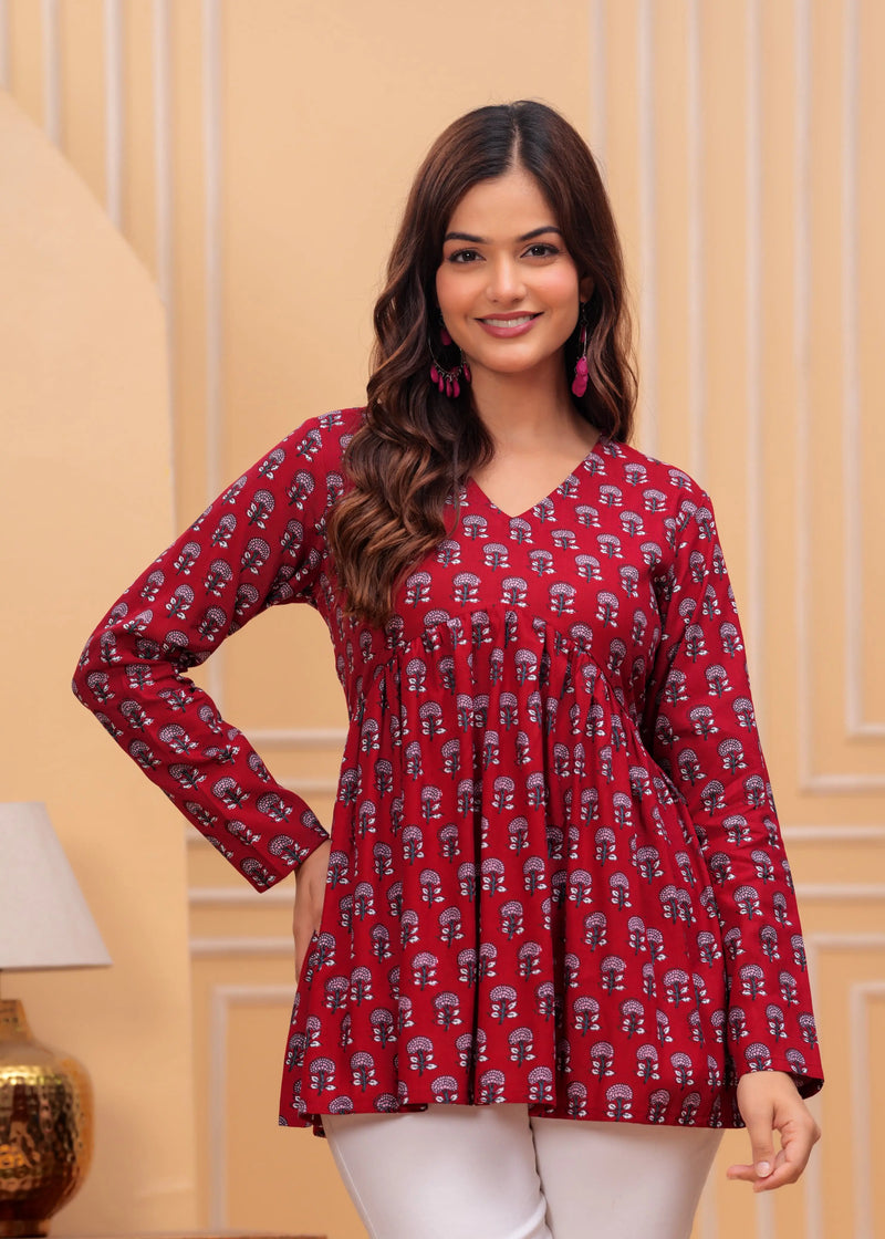 Red printed long kurti top with V-neck and flared hem, styled with long sleeves.