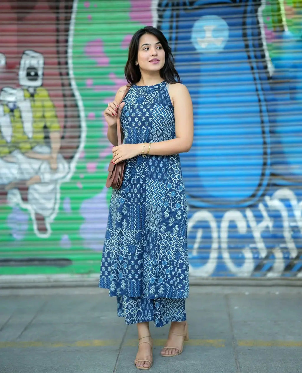 Blue sleeveless printed kurti with matching palazzo pants on model against colorful graffiti wall.