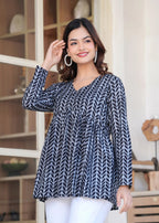 Black and white printed long kurti top with V-neck and full sleeves on model.