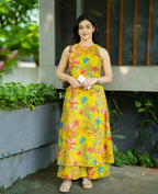 Yellow sleeveless dress with colorful floral print and tiered hem, modeled outdoors.