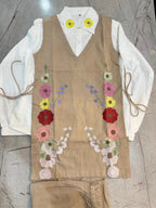 Beige linen corset with colorful floral embroidery over white long-sleeve blouse.