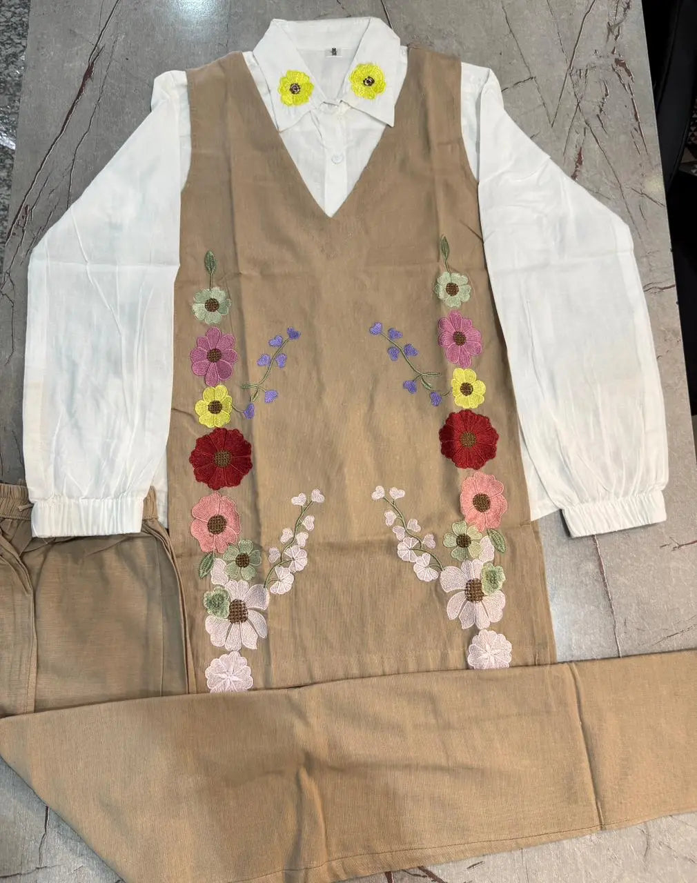 Beige corset-style dress with floral embroidery and white puffed long sleeves.