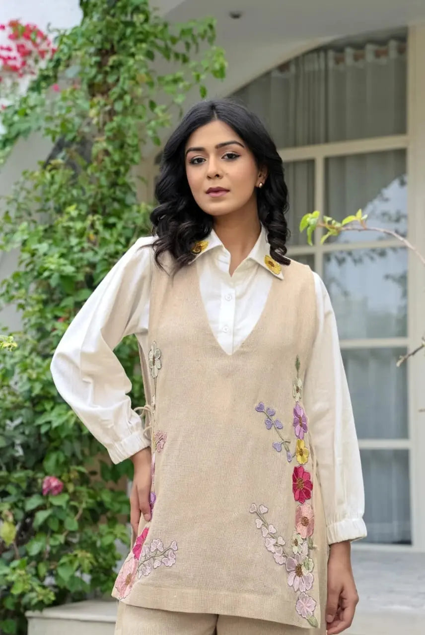 Beige floral embroidered corset layered over white long-sleeve collared blouse.