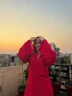 Red corset with long puffed sleeves and a v-neckline worn outdoors at sunset.