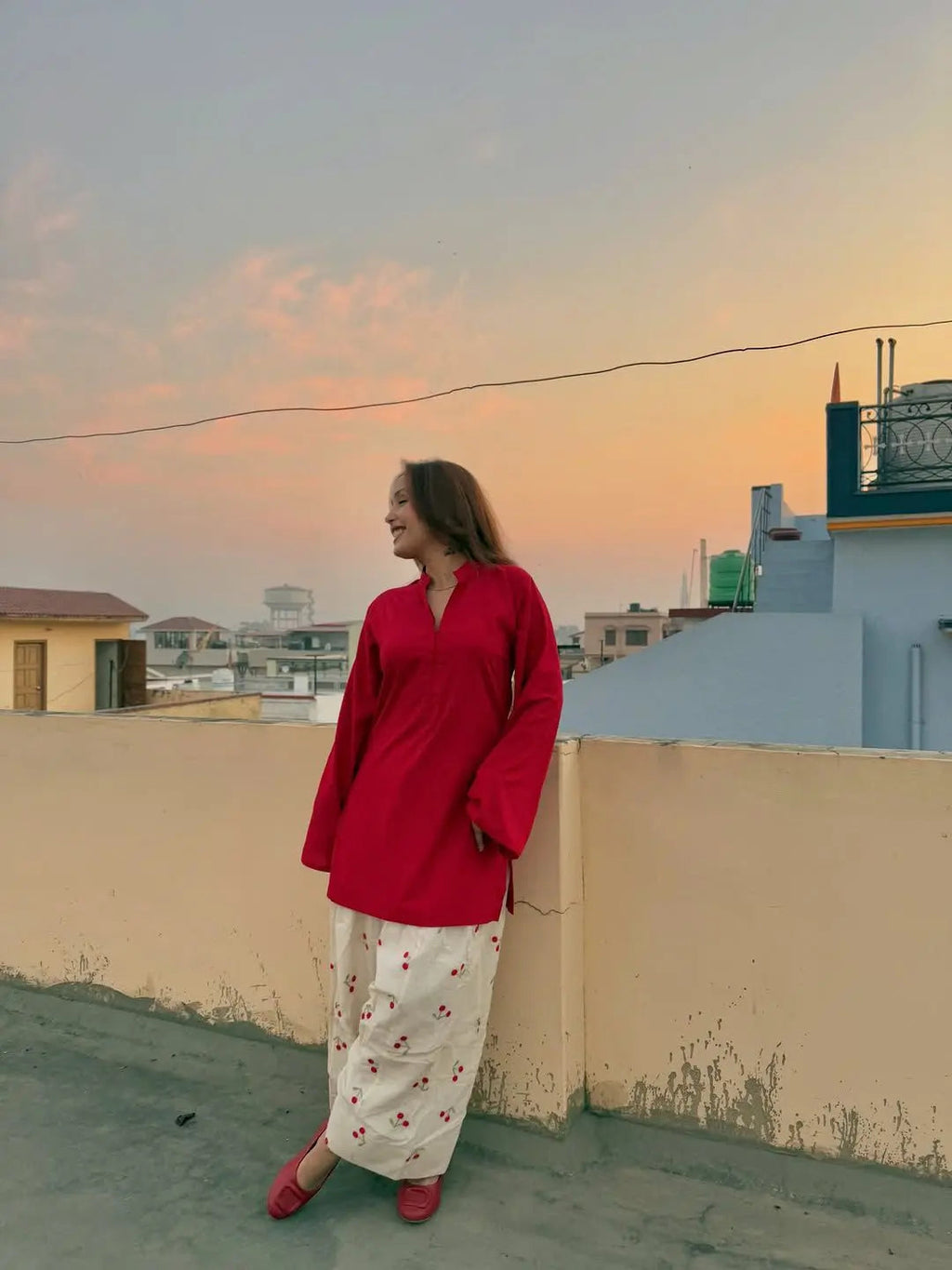 Red corset worn over a floral white maxi dress with long sleeves, styled outdoors at sunset.