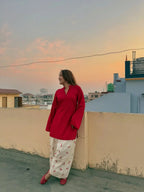 Red corset worn over a floral white maxi dress with long sleeves, styled outdoors at sunset.