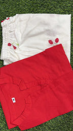 Red corset-style top with front lace-up detail, laid flat on green grass.