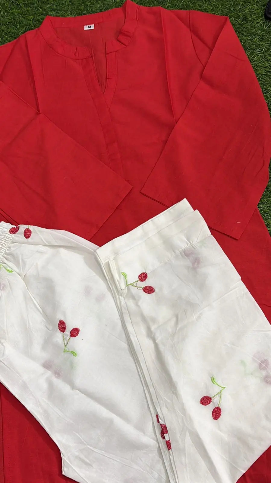 Bright red corset with structured seams paired with white pants featuring small cherry prints.