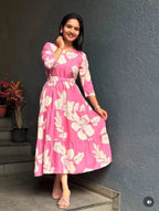 Pink midi dress with white floral print, three-quarter sleeves, and a gathered waist.