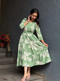 Light green midi dress with large white floral print and long sleeves, styled with pink flats.