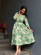 Light green midi dress with large white floral print and long sleeves, styled with pink flats.