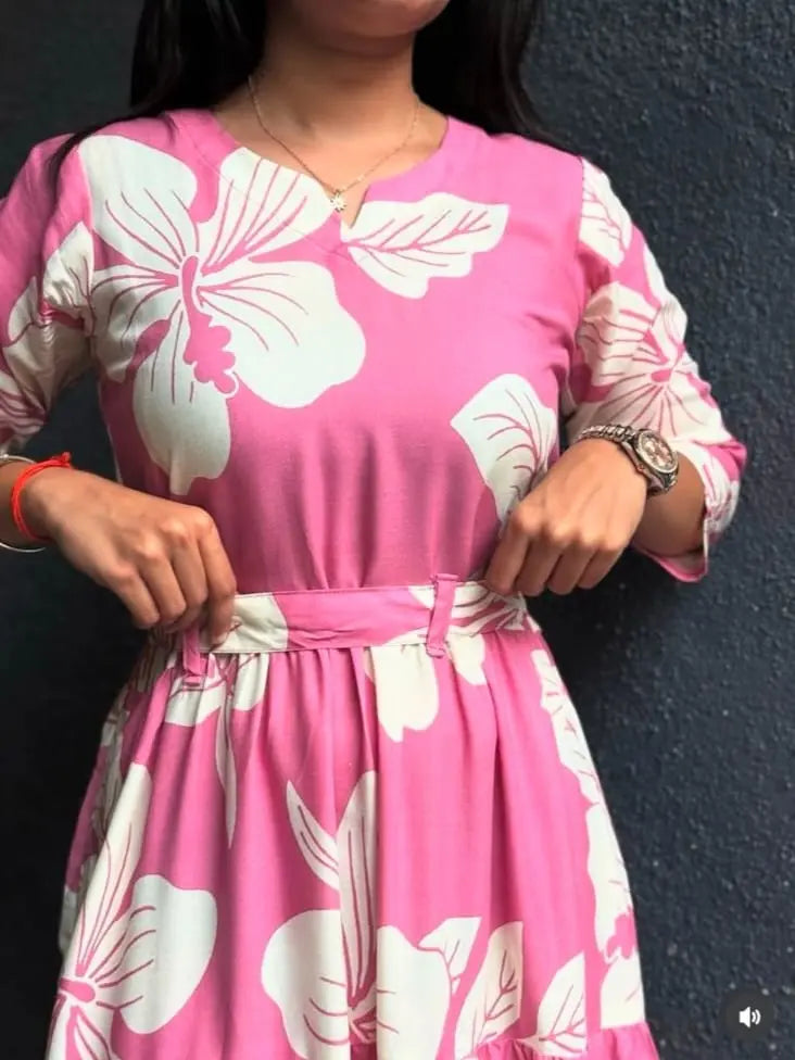Pink short dress with large white floral print and gathered waist detail.