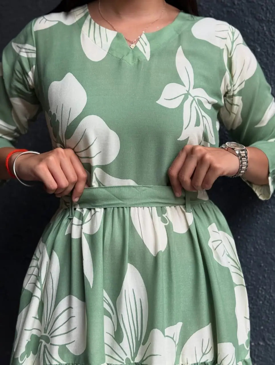 Green dress with large white floral print, V-neck, 3/4 sleeves, and a waist tie belt.