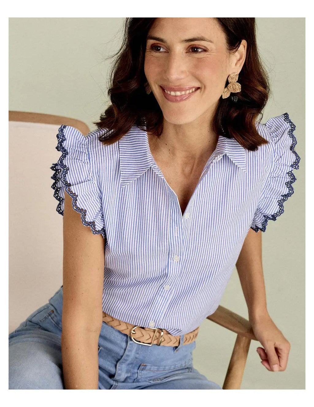 Blue striped blouse with scalloped lace trim sleeves and button-down front, worn with light jeans.