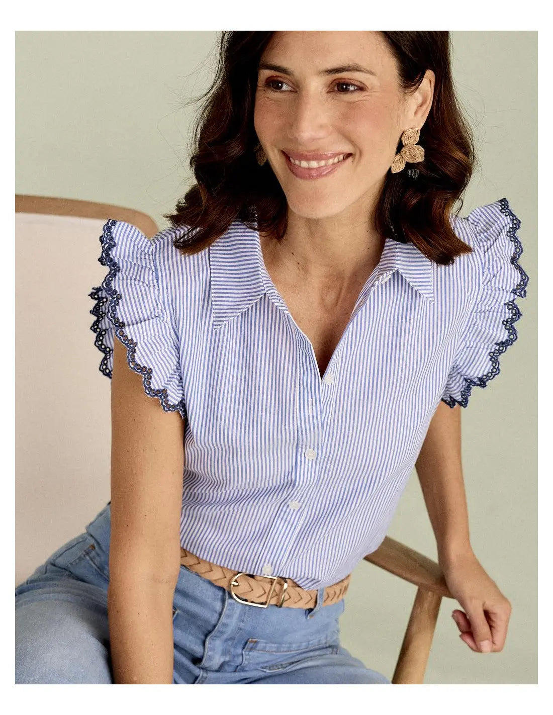Blue striped blouse with scalloped lace trim sleeves and button-down front, worn with light jeans.