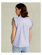 Blue sleeveless blouse with lace-trimmed ruffled sleeves and vertical stripes, worn with light denim jeans, shown from back.