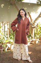 Brown long-sleeve tunic with front pockets paired with cream wide-leg pants featuring brown floral prints.