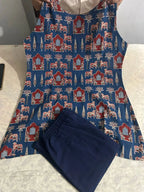 Blue and red patterned sleeveless dress with floral and geometric motifs paired with navy blue pants.
