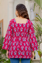 Pink cotton A-line kurti with blue floral print, square neckline, and flared long sleeves.