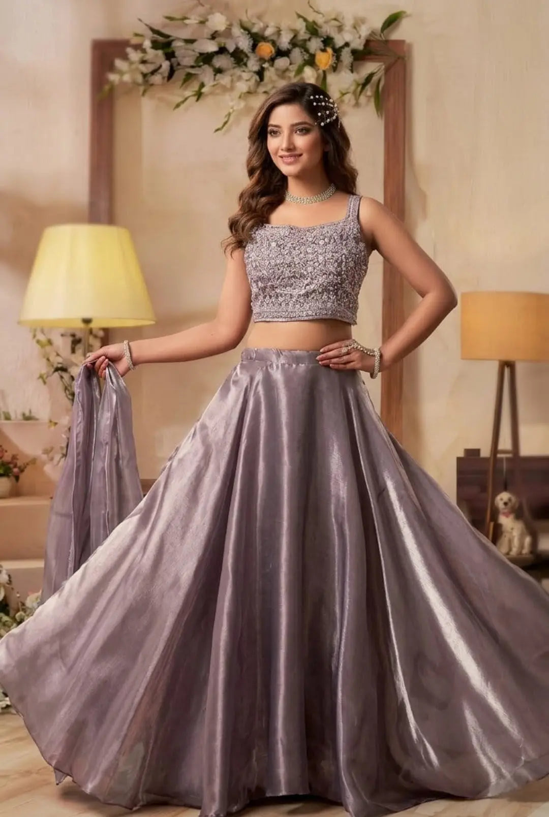 Grey satin lehenga set with sleeveless crop top and flared skirt, styled with matching dupatta and floral headpiece.