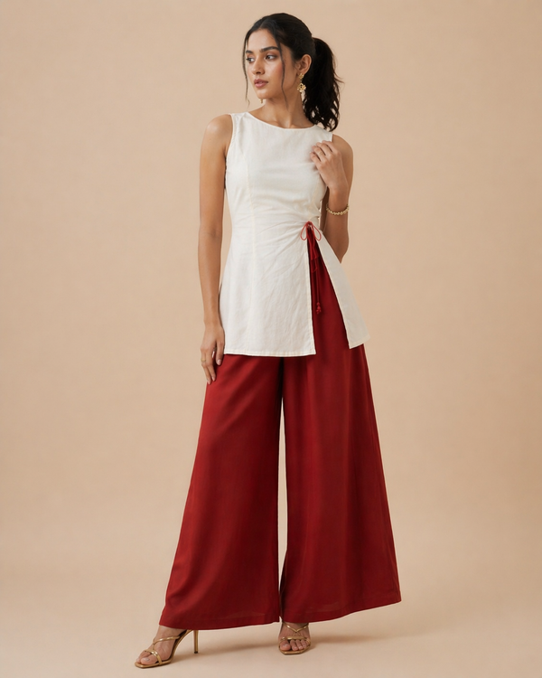 Ivory sleeveless wrap peplum top paired with wide-leg rust red pants and tan heels.