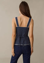 Navy blue sleeveless peplum top with white polka dots and lace trim, tied back bow detail.