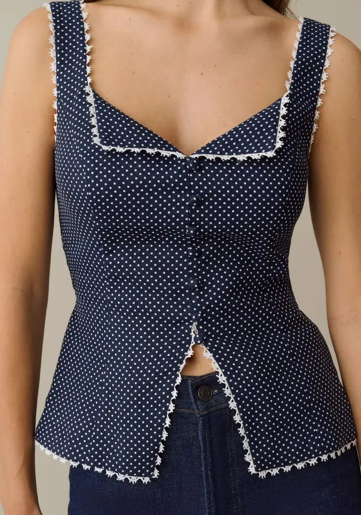 Navy blue sleeveless peplum top with white polka dots and scalloped trim on neckline and hem.