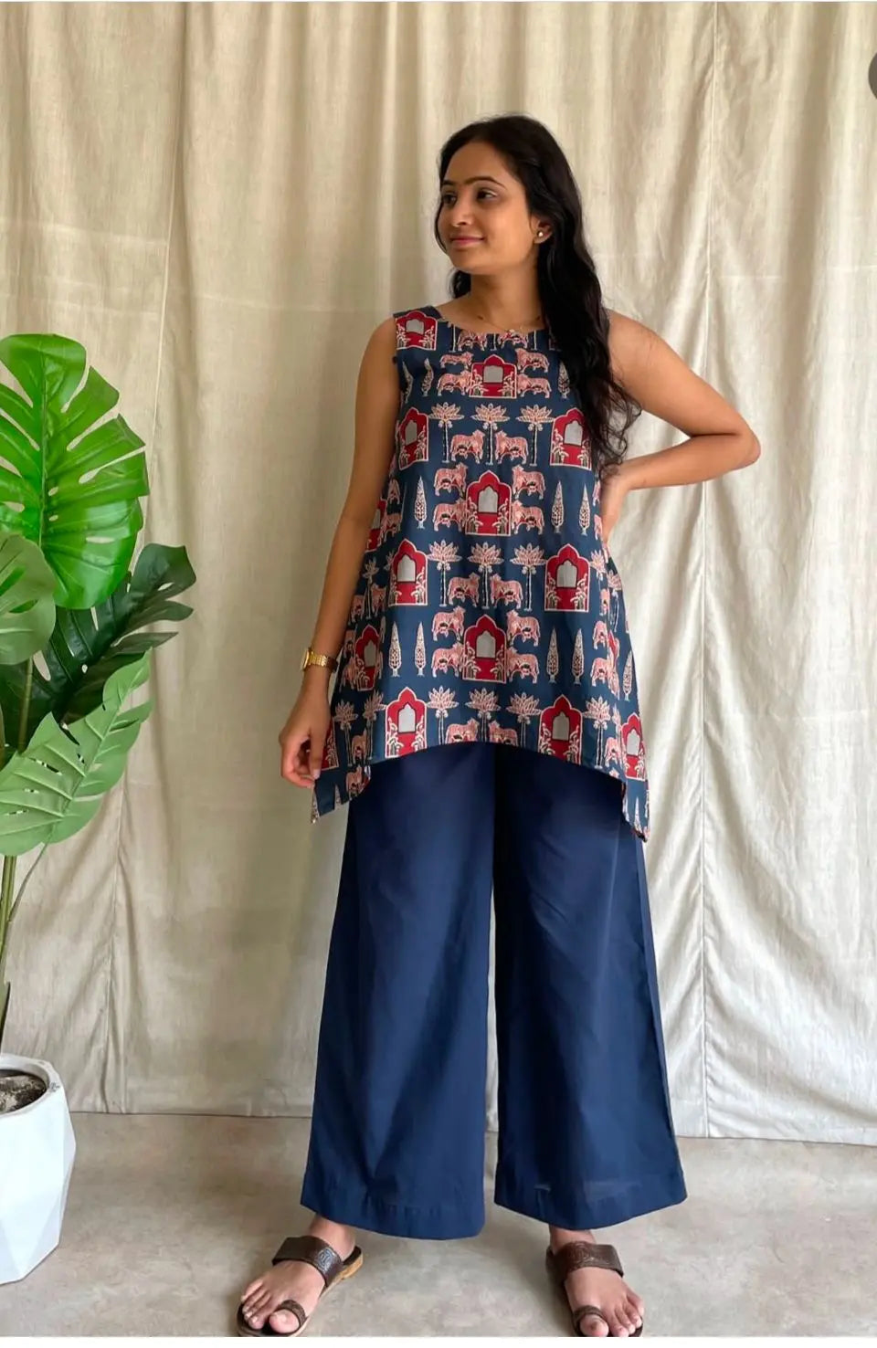 Navy sleeveless tunic with red and beige abstract print paired with wide-leg navy pants.