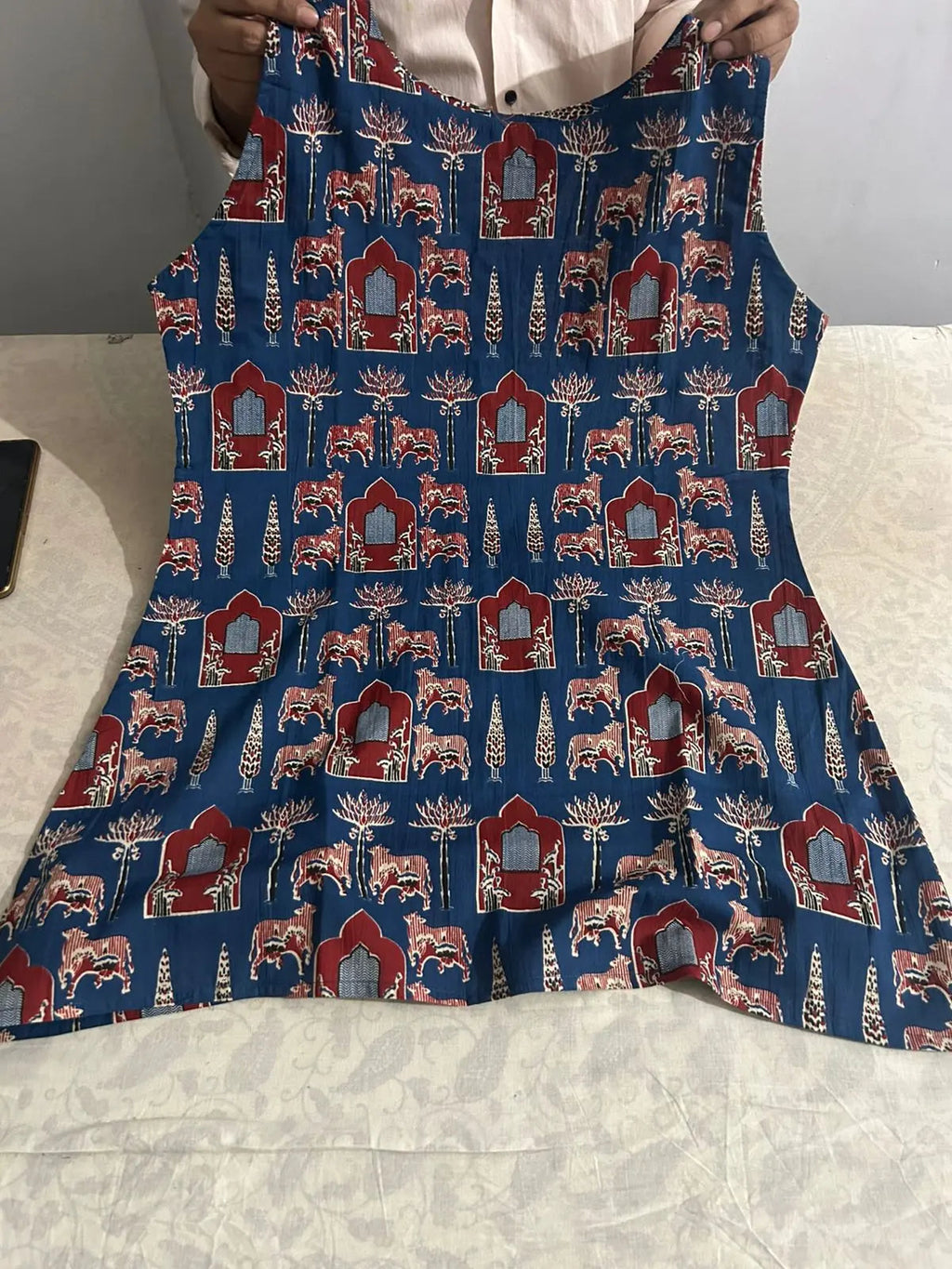 Blue apron with red, white, and beige intricate floral and geometric patterns, tied at the waist.