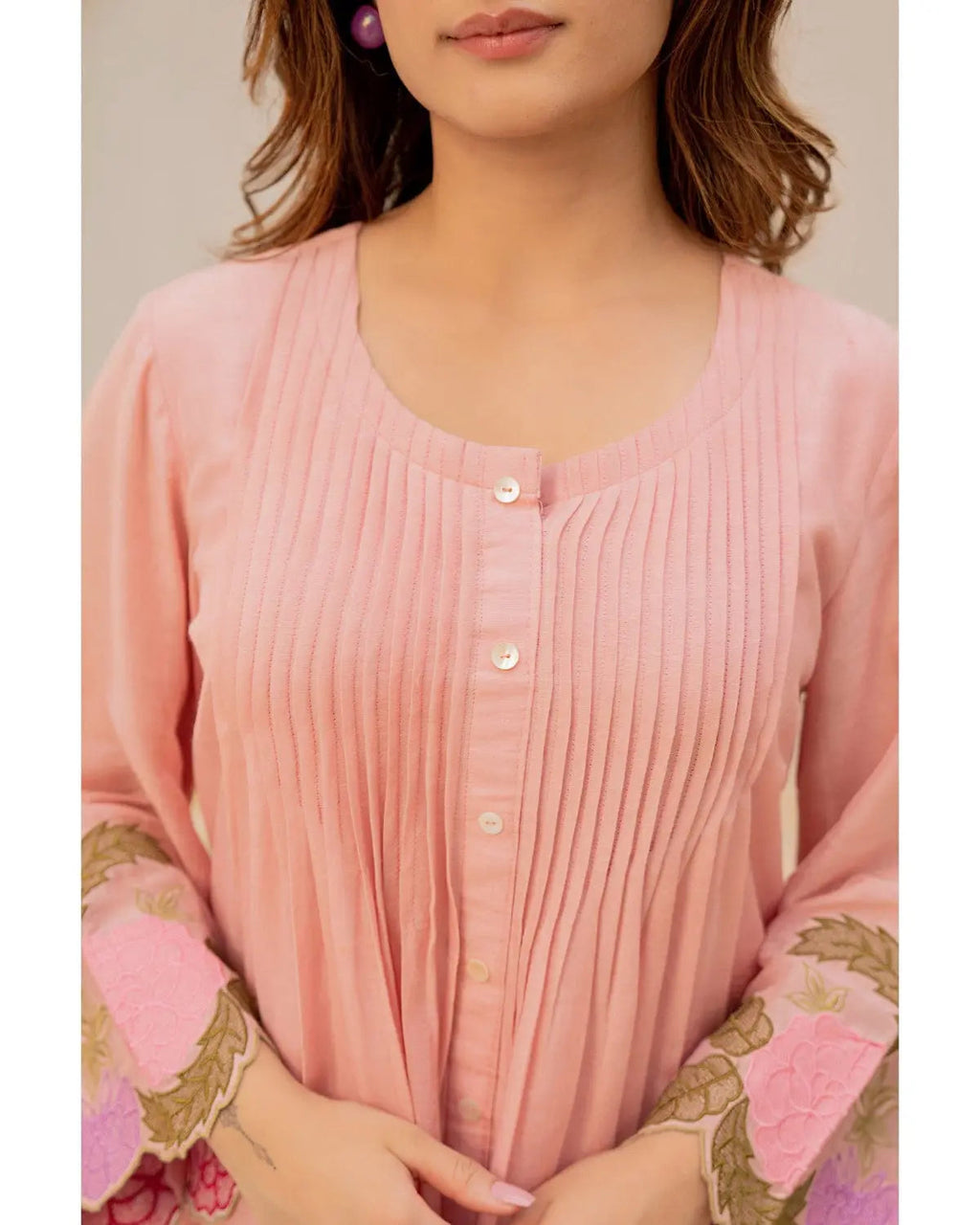 Peach cotton kurta with vertical pleats, round neckline, button-front, and floral embroidered sleeves.