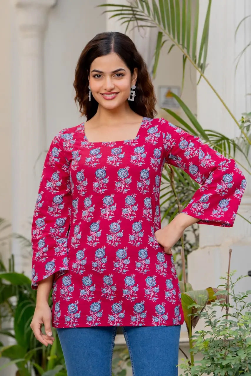 Pink cotton A-line kurti with blue floral print, square neckline, and flared 3/4 sleeves.