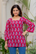 Pink cotton A-line kurti with blue floral print, square neckline, and flared 3/4 sleeves.