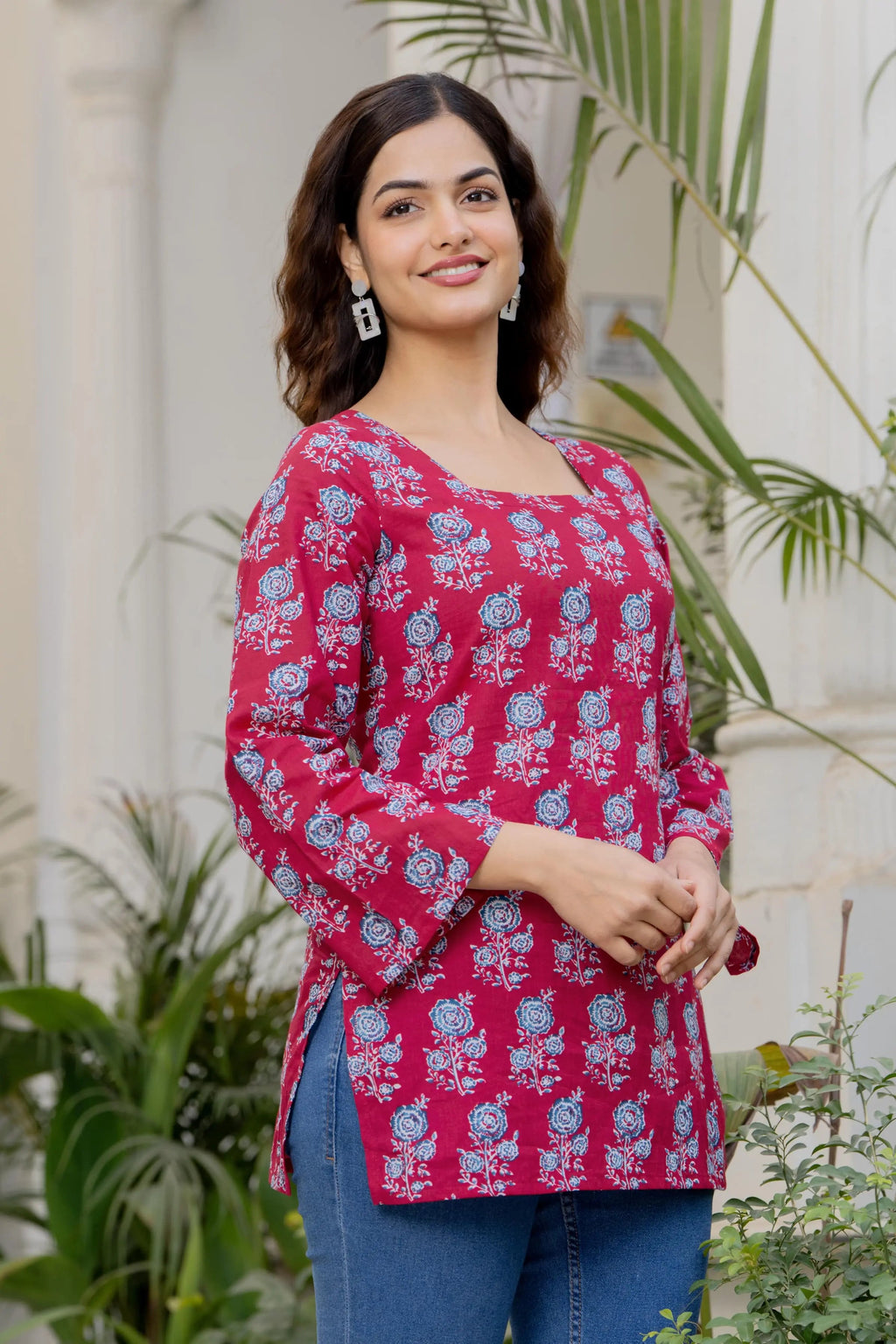 Pink cotton kurti with blue floral print, square neck, and flared long sleeves.