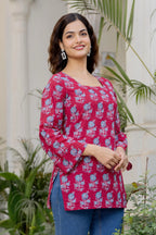 Pink cotton kurti with blue floral print, square neck, and flared long sleeves.