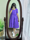 Purple midi dress with short sleeves, button front, and white floral embroidery paired with white sneakers.