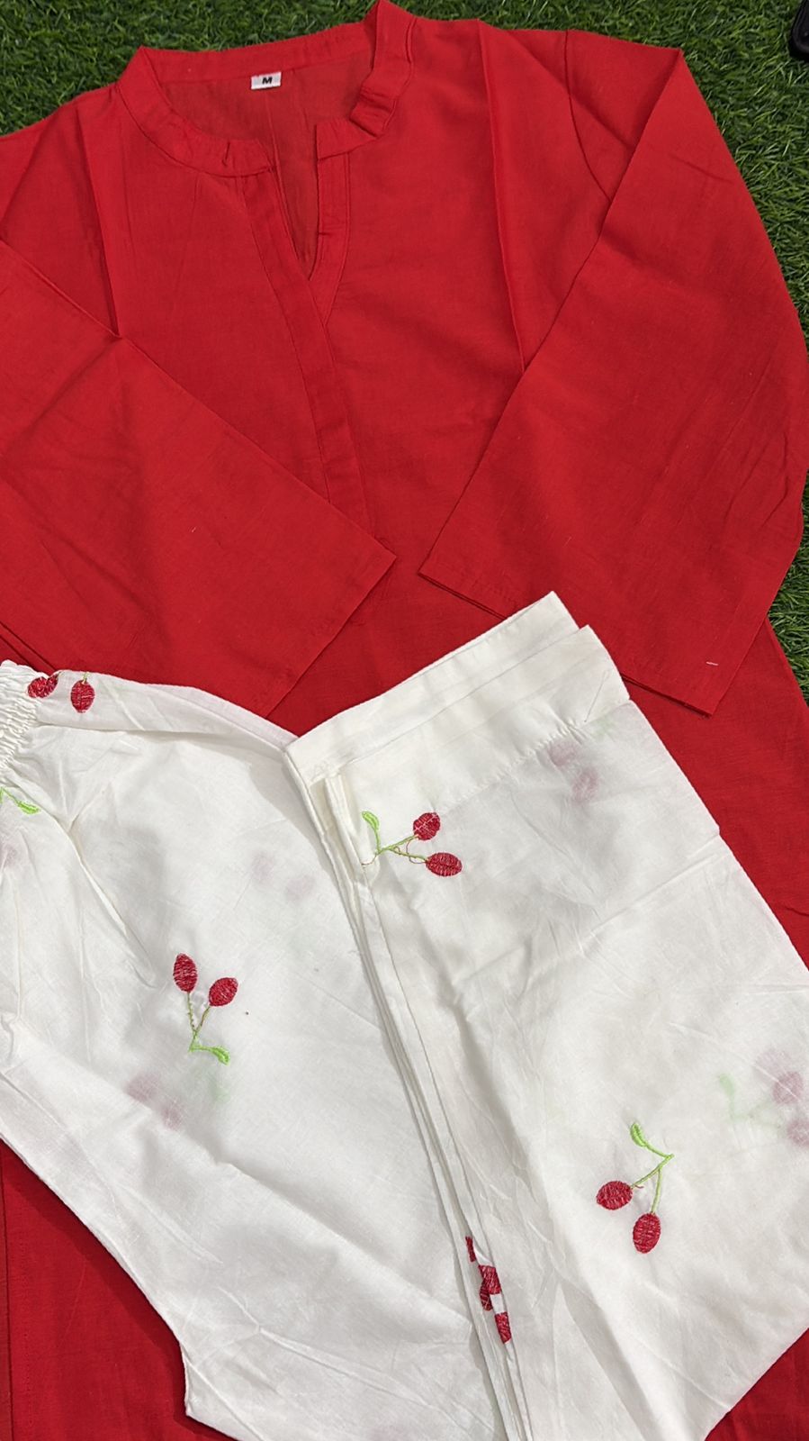 Red long-sleeve tunic paired with white pants featuring red cherry embroidery.