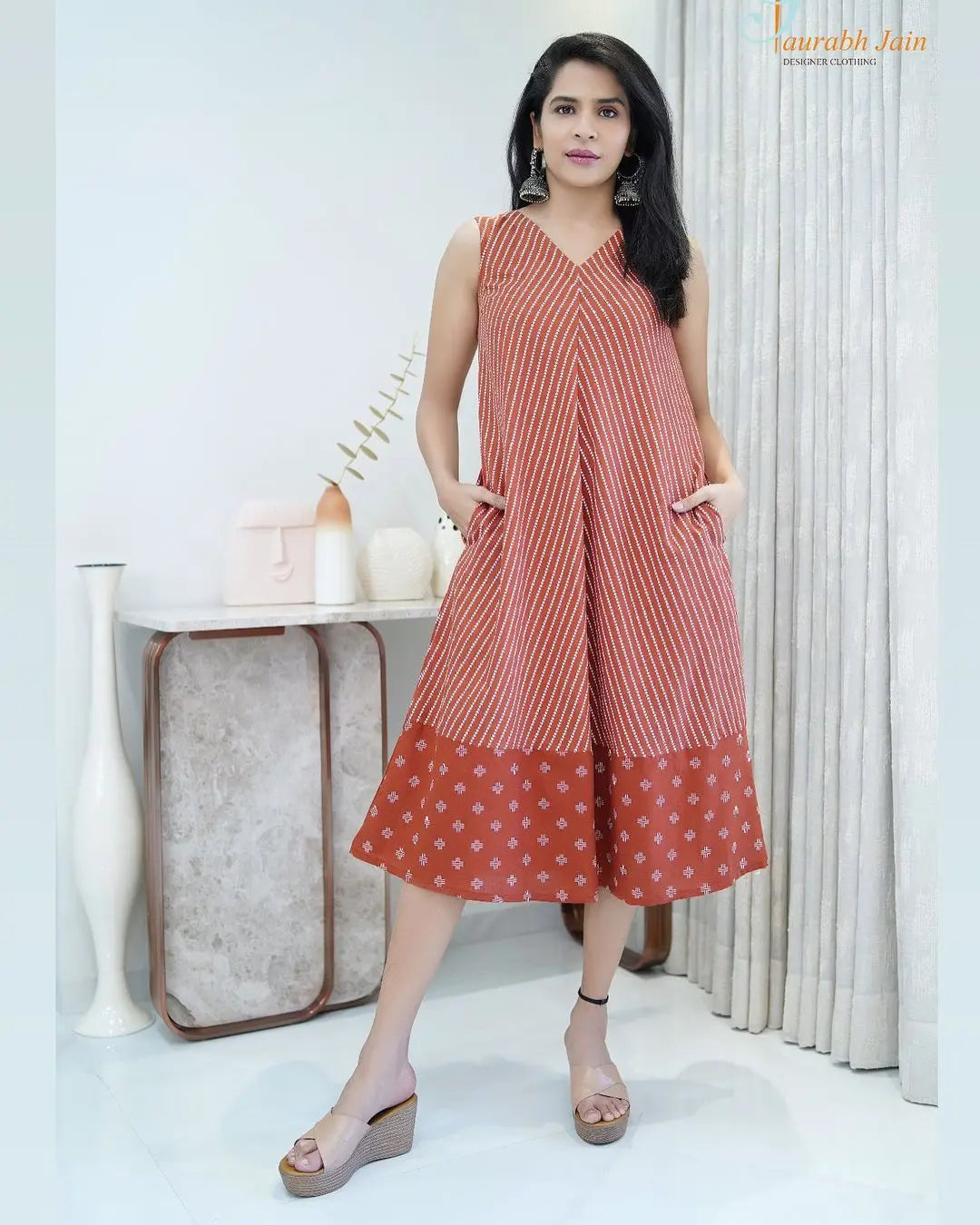 Sleeveless rust-orange midi dress with white polka dots and contrasting hem detail.