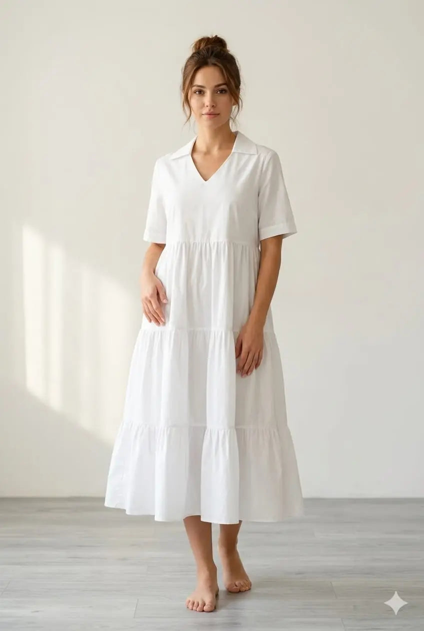 White midi dress with V-neck, short sleeves, and tiered skirt on a standing model.